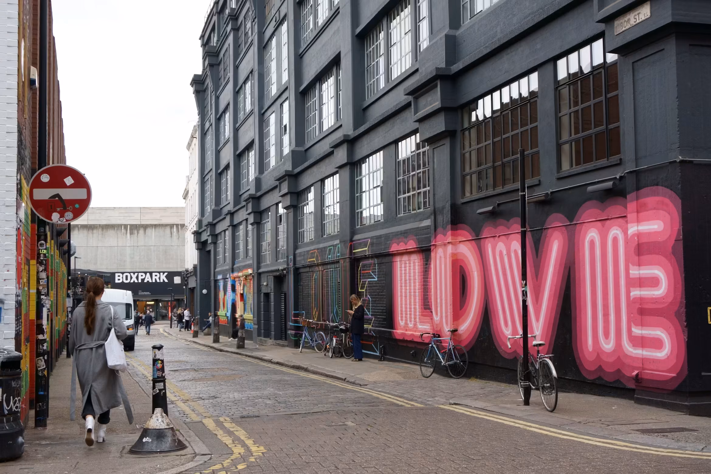 Street art and pedestrians on a Shoreditch side street near Boxpark