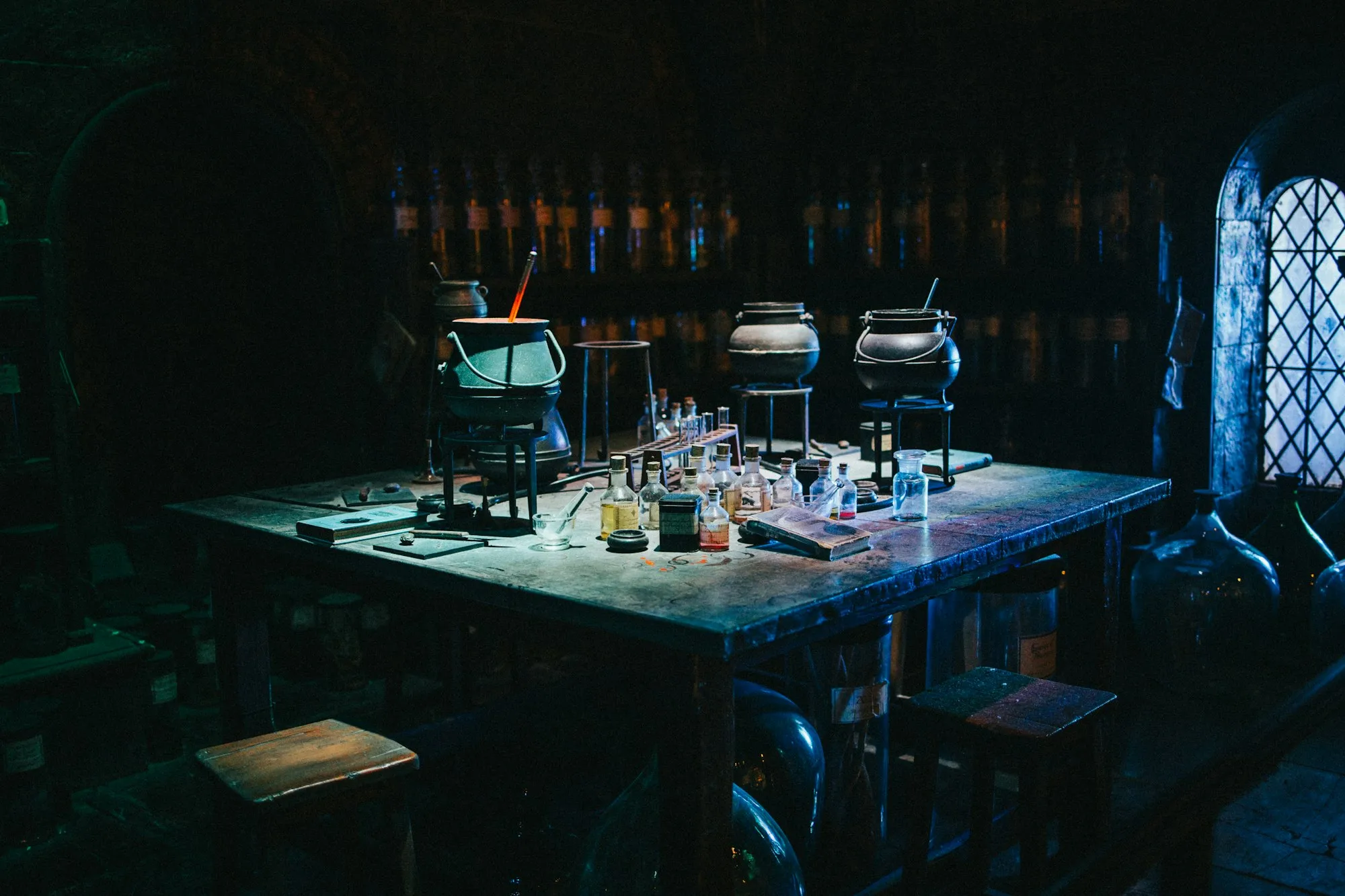 Cauldrons and potion bottles set up on a table in the Potions Classroom set