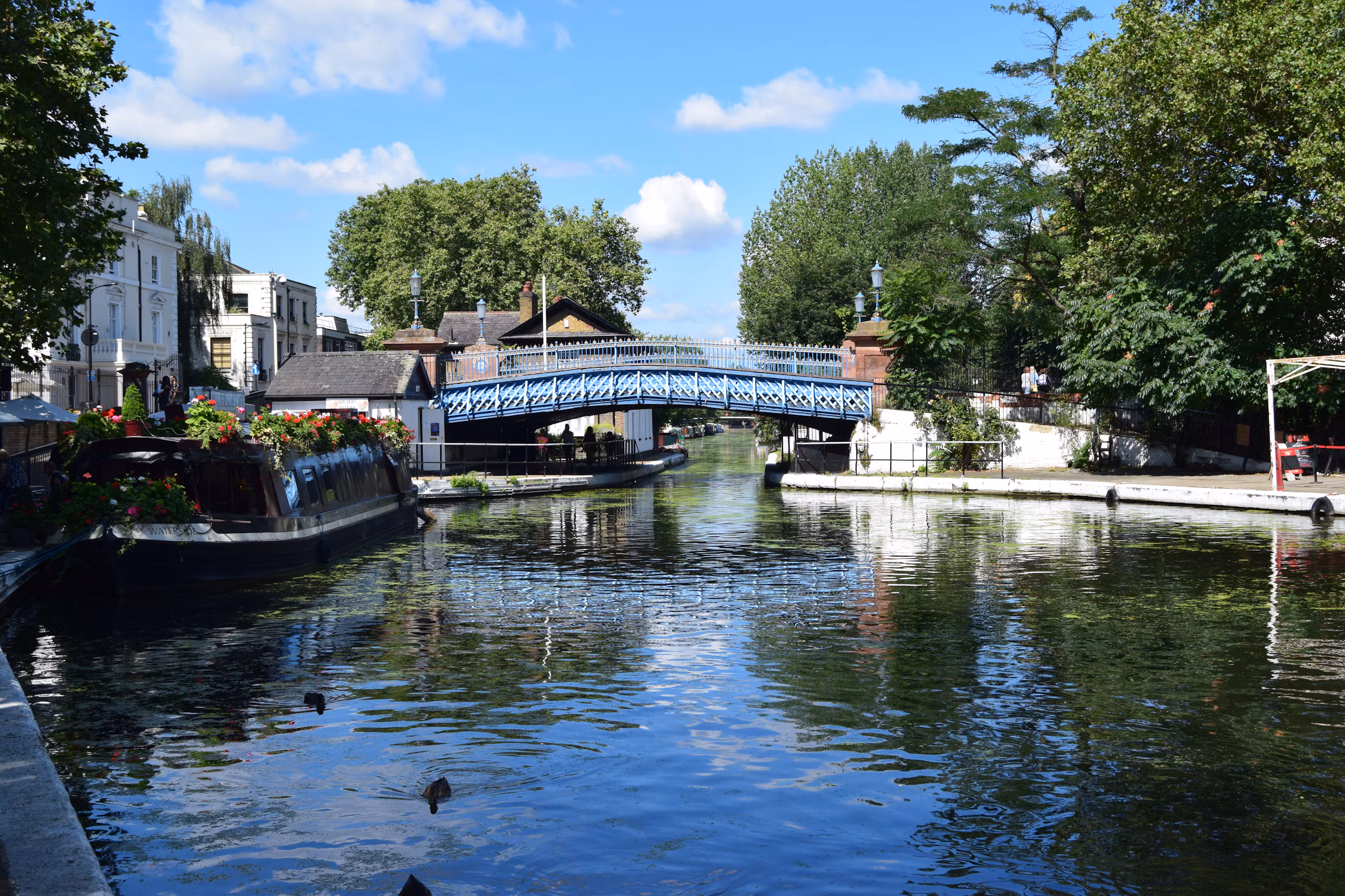 Canal boats and a blue footbridge beside the water at Little Venice