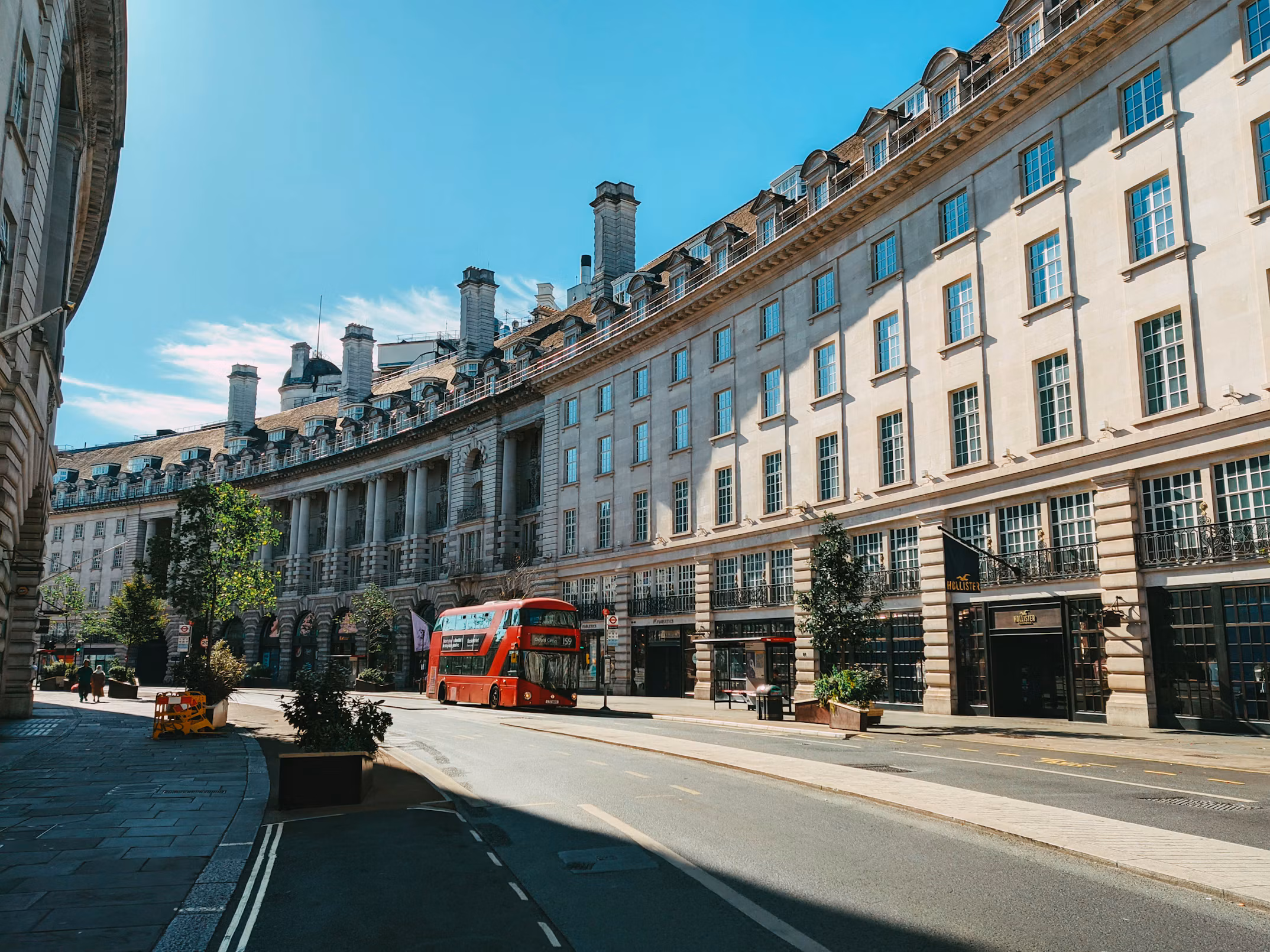 A red double-decker bus on a curved London street lined with grand stone buildings