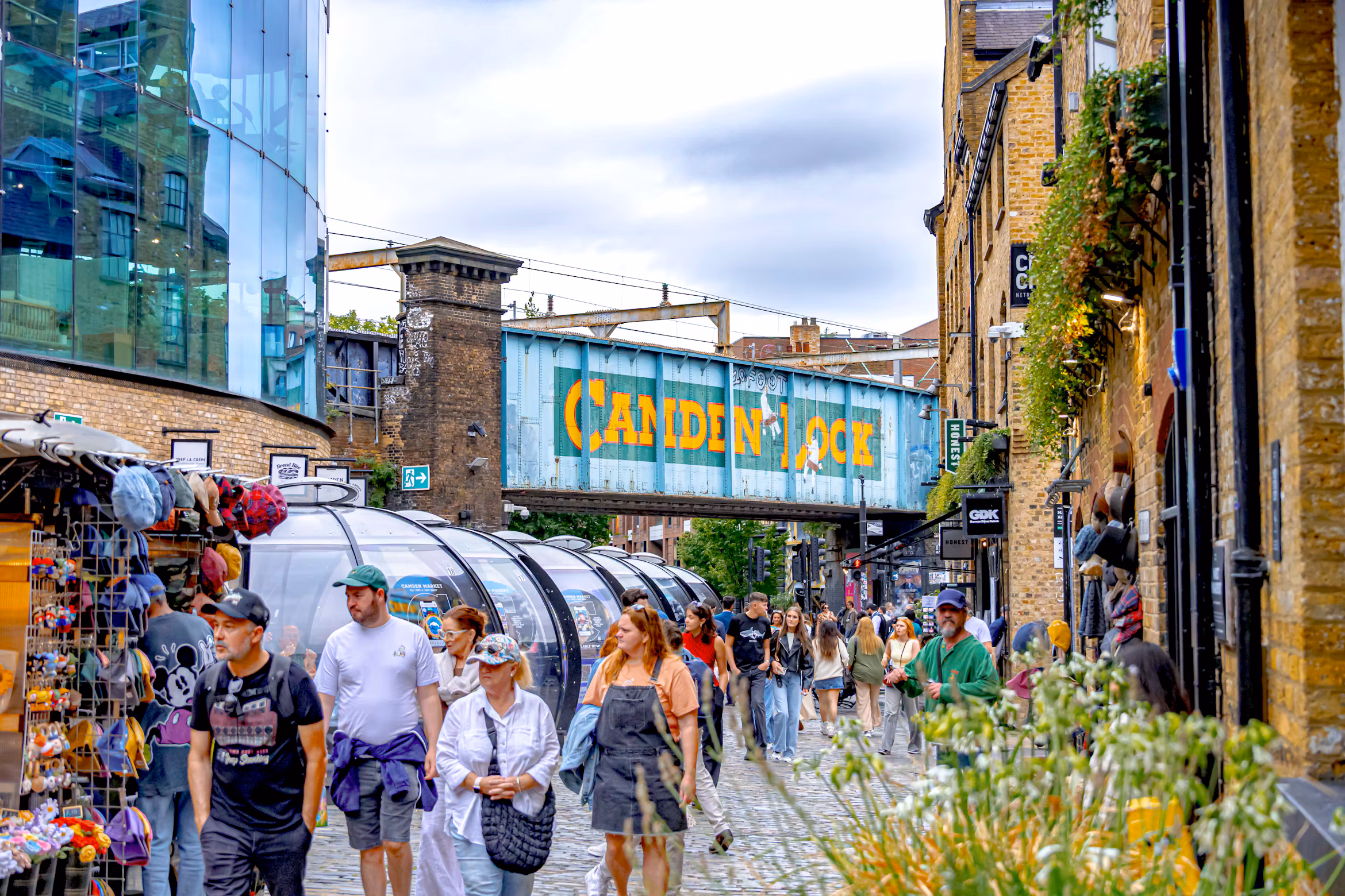 Visitors browsing shops below the Camden Lock railway bridge sign